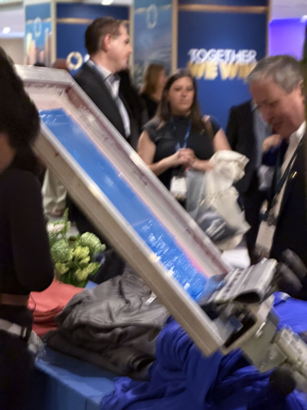 Team members showcasing a printed apparel sample at an event booth